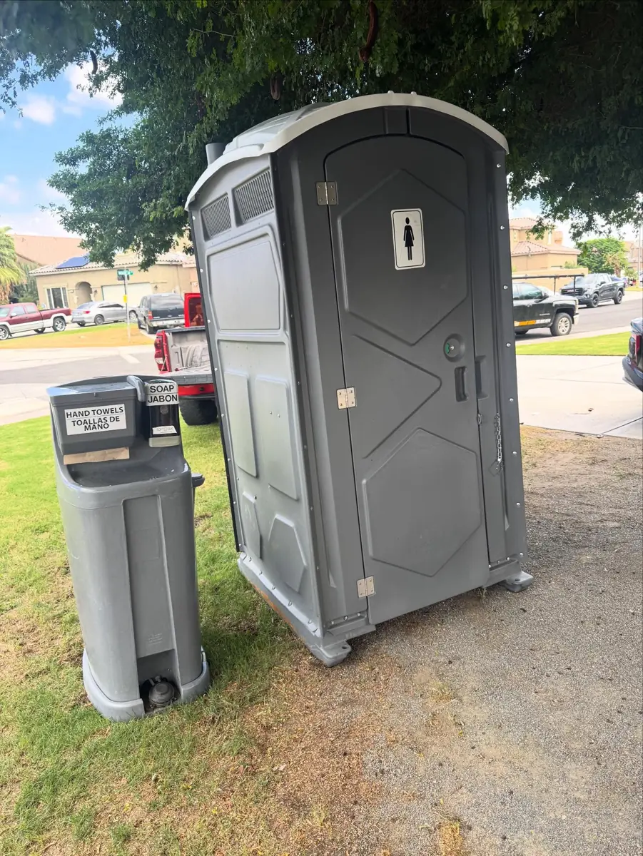 Gray handwashing station beside a porta potty